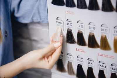 Hair bundles displayed in different colors that are available for purchase against white brick wall.