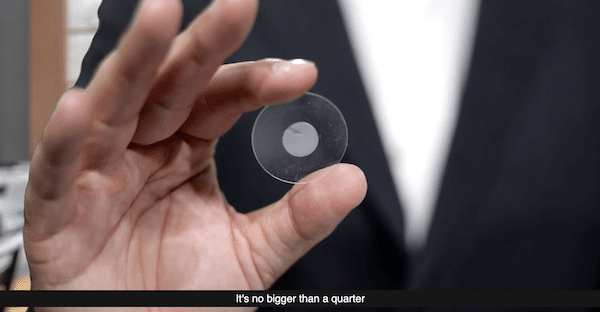 Ian King holding a tiny disk representing a small memory storage device.
