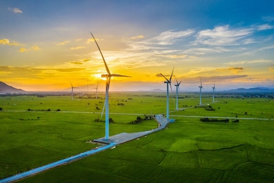 Landscape with wind turbines for electric power production located on a large green field.